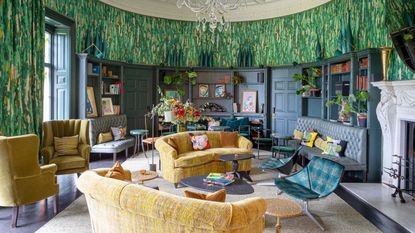 large living room with patterned green curved walls and curved inbuilt bookshelves and yellow sofas 