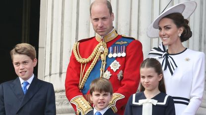 Kate Middleton wears a white dress with navy accents and a matching hat as she joins her husband, Prince William, on the Buckingham Palace balcony