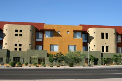 red, orange, and tan apartment building with plants out front