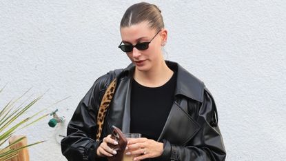 Hailey Bieber leaves her Pilates studio on Jan. 5 wearing a leather trench coat with her Saint Laurent tote bag and ballet flats by The Row