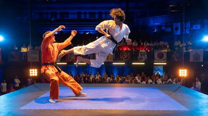 Xolo Maridueña as Miguel Diaz (right), hitting an opponent with a flying kick, in &#039;Cobra Kai.&#039;