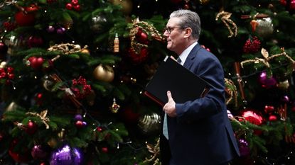 Keir Starmer walks past the Downing Street Christmas tree with government papers in his hand