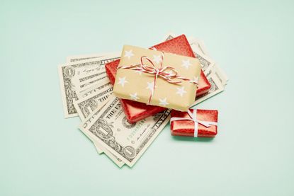 three presents on an array of one dollar bills against a pale green background