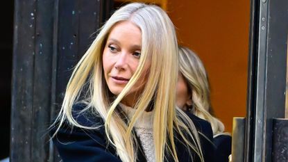 Gwyneth Paltrow films a commercial in a black coat and a cable knit sweater