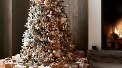 Holiday ornaments on a Christmas tree beside a fireplace.