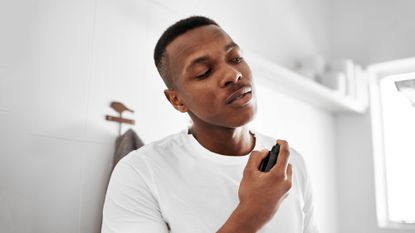 A man spraying one of the best men’s fragrances onto his neck