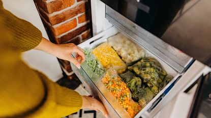 An open freezer drawer full of bags of cut up vegetables