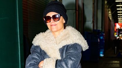 Katie Holmes wears a shearling coat with an oversize collar with a black beanie and velvet pants while on her want to her Broadway show