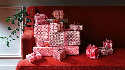 Pile of red and white wrapped christmas presents on a red sofa