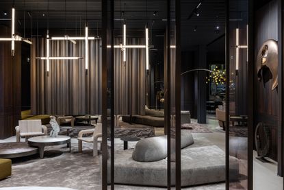 A dramatic furniture showroom features sculptural lighting and seating in neutral shades of grey and brown.