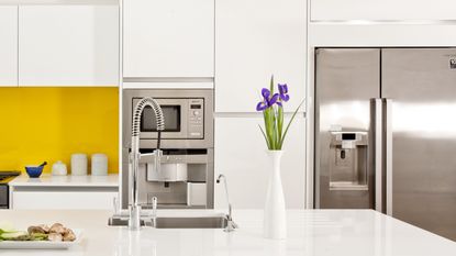 A white kitchen with a yellow splashback and American-style fridge freezer