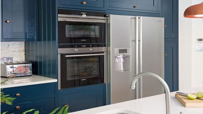 dark blue kitchen cabinets with silver fridge freezer and double oven