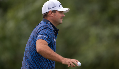 Patrick Reed waves to the crowd after holing a putt