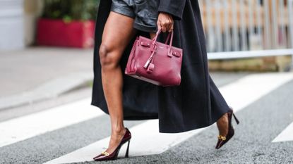 A woman crossing the road holding a YSL tote bag