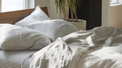 Brooklinen Linen Duvet Cover Set on a wood bed frame against a white wall.