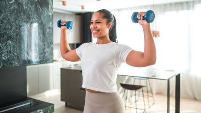 Woman holding dumbbells in a kitchen