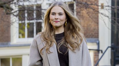 Princess Catharina-Amalia in a black top, wide leg jeans and and a gray overcoat at a photo call in November.