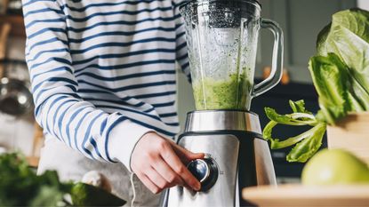 A woman turning on a blender