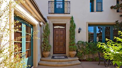 A Mediterranean home with topiaries and a welcome mat for added curb appeal