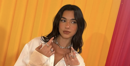 dua lipa wears a white button-down dress and feathered heels from ferragamo