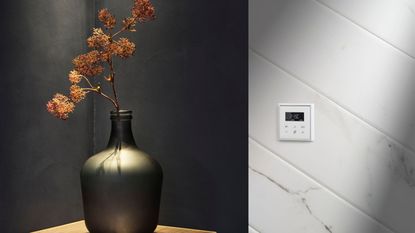 A white thermostat on a white wall, beside a sideboard with a grey vase with some dried flowers