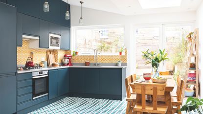 Kitchen extension with L-shaped kitchen diner, blue units, yellow tiles and patterned floor with a rooflight above