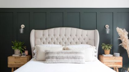 White painted bedroom with dark blue panelling behind a white bed with cream headboard