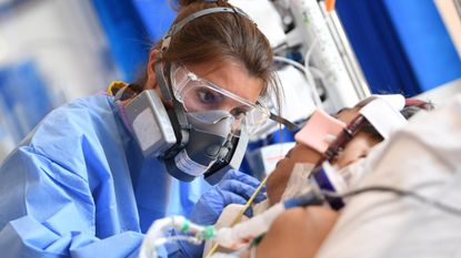 A doctor in PPE cares for a Covid patient.