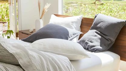 Brooklinen linen bedding on a bed against a window with a garden view.