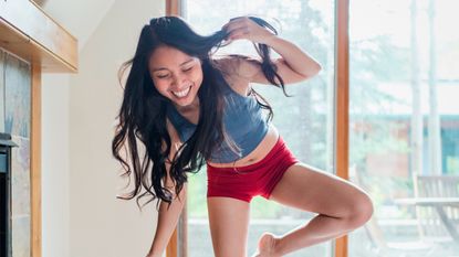 Smiling woman balancing on one leg