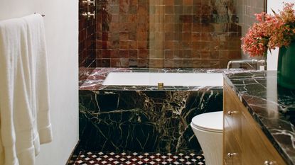 a bathroom with a black marble bathtub and a red tiled wall