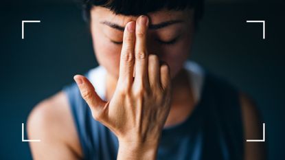 Woman holding fingers to forehead with eyes closed, representing the question of does face yoga work