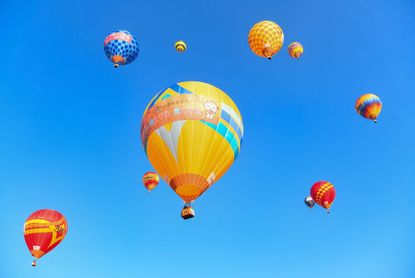 Hot air balloons rising against a blue sky