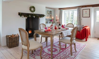 Cottage dining room with log burner decorated for Christmas with simple white and red decor 