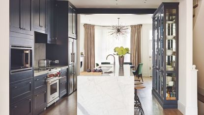 Open-plan blue kitchen with white marble island