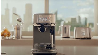 Breville Bambino vs Breville Bambino Plus: Breville&#039;s bambino plus espresso machine on a countertop with a window looking over the city in the background