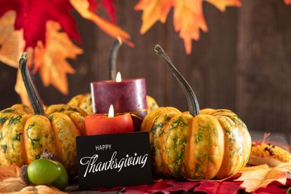 Happy Thanksgiving sign surrounded by lit candles and pumpkins