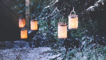 Wintry flower bed with snow and stakes with night paper lanterns