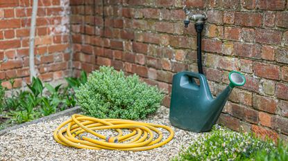 A garden tap with a hose and watering can