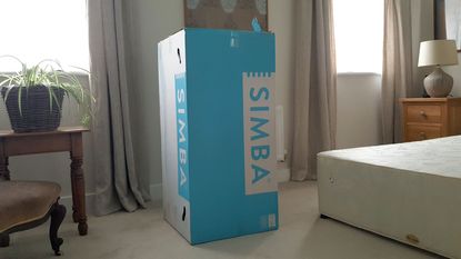 A Simba mattress in a branded turquoise and white box in a bedroom