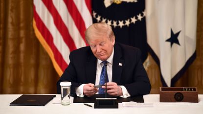 President Donald Trump looks at a pre-paid debit card during a meeting with his Cabinet on May 19, 2020 