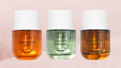 Three glass bottles of PHLUR perfumes are pictured on a pink watercolour paint-style template, including a press shot of the Tangerine Boy scent (which is orange), the Father Figure scent (green) and the Somebody Wood perfumes (with is brown-amber).