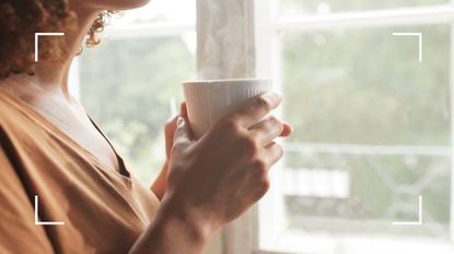 Woman&#039;s hands holding steaming cup standing next to the window, representing how to avoid alcohol