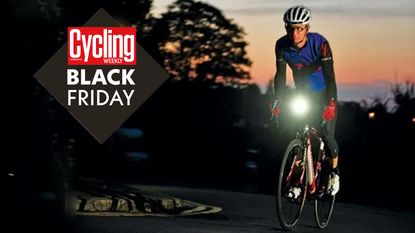 Male cyclist riding his bike in the dark with red sunset sky