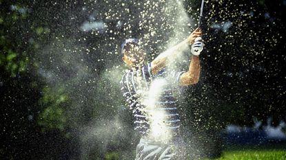 Tiger Woods blasts out of a bunker