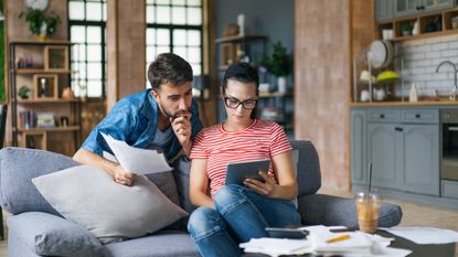 Couple calculating savings options at home using tablet and calculator