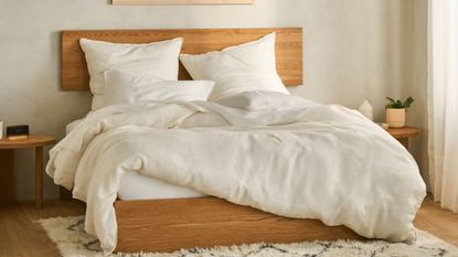 White sheets and pillows on a bed against a white wall.