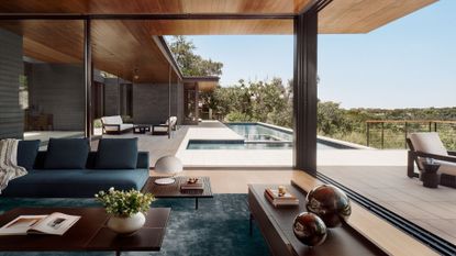 A bright and airy living room with floor to ceiling windows opening onto the outdoor deck and pool