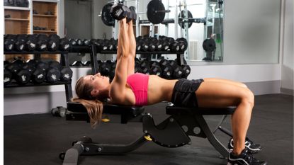 woman on the best weight bench doing dumbbell press