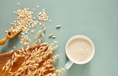 Oat milk in a glass and mug on a blue background